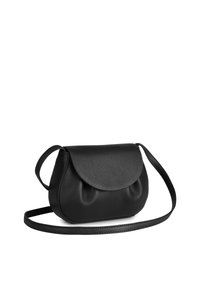 Svart läder crossbody-väska med rundad form, slät yta och klaffstängning. Har en tunn, justerbar rem.