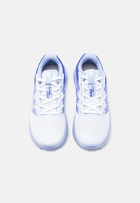 Ζευγάρι λευκών και μπλε αθλητικών παπουτσιών με λευκά κορδόνια, επάνω μέρος από διχτυωτό υλικό και το κείμενο «ALPHA GLIDE» στη γλώσσα, σε γκρι επιφάνεια, από πάνω.