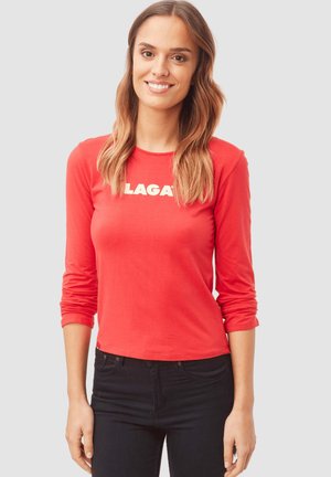 Camiseta roja de manga larga con la palabra "LAGAR" en blanco, fabricada en tejido suave, con un diseño ajustado y cuello redondo.
