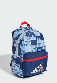Mochila de tela azul con un diseño de patchwork que presenta gráficos de Mickey Mouse, un bolsillo con cremallera roja y acentos de logo. Textura suave con correas acolchadas.
