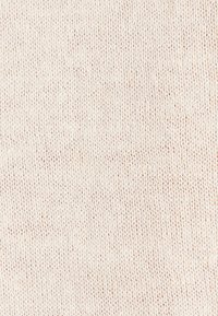 Vue rapprochée d’un tissu tricoté doux, blanc cassé, avec une texture de maille fine et uniforme.