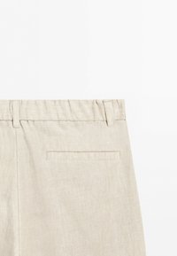 Beige linen trousers with a waistband, belt loops, and a single horizontal back pocket, shown against a plain white background.