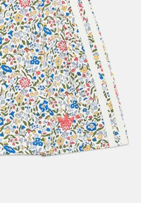 Blumenmusterstoff mit blauen, gelben, roten und grünen Blumen auf einem weißen Hintergrund; enthält weiße Seitenstreifen und ein rotes Logodetail.