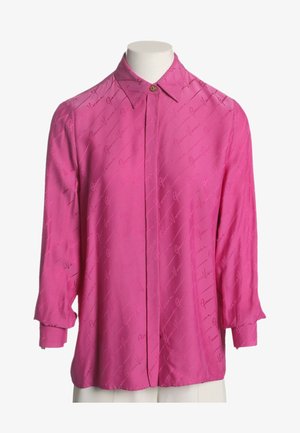 Langærmet, knaldrød bluse med spids krave og subtilt diagonalt skriftsmønster, knappet ved halsen, vist på en hvid mannequin.