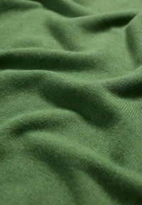 Tejido de punto verde con una superficie suave y texturizada, que muestra una apariencia lisa y caída, y una notable elasticidad.