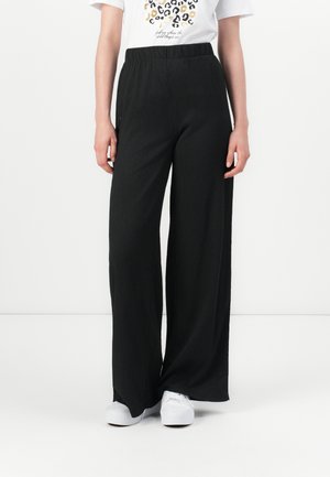 Black wide-leg pants with an elastic waistband, featuring a textured fabric and a flowy design, paired with white sneakers.
