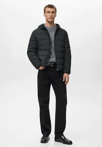 Zwarte pufferjas met een capuchon, daaronder een grijze trui met textuur, gecombineerd met zwarte jeans en glanzende zwarte loafers. Eenvoudig, functioneel ontwerp.