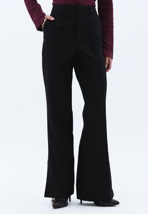 Zwarte wijde broek met een gladde textuur, hoge taille en voornaaddetails. Gepaard met puntige zwarte hakken.