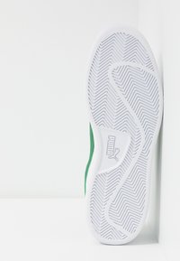 Zielone sneakersy z teksturowaną białą gumową podeszwą, ozdobioną wzorem w jodełkę i logo Pumy z boku. Wykonane z lekkich materiałów.