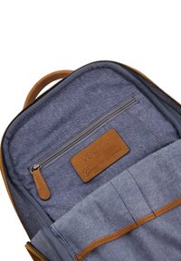 Blue fabric backpack interior with leather accents, zippered pocket, and organizational slots. Label reads "Venezia Genuine Leather."