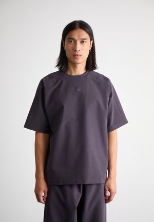 Korte mouwen, donkerpaarse sportshirt met een ronde hals, gestructureerde zijaccenten en een klein logo op de borst. Zacht, lichtgewicht stof.