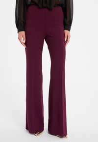 Pantalons larges bordeaux en tissu lisse avec un design uni, dotés d'une taille ajustée et d'un ourlet évasé pour un look sur mesure.