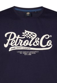Tmavě modré bavlněné tričko s velkým bílým grafickým nápisem „Petrol & Co“ doplněným o šachovnicovou vlajku a další text pod ním.