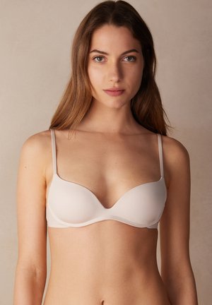 Licht beige gepadded bh met dunne verstelbare bandjes, zachte textuur, diep decolleté en naadloos ontwerp voor discreet dragen onder kleding.