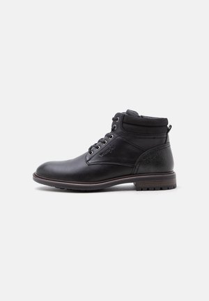 Bottine en cuir noir avec lacets, col rembourré et talon texturé, avec une semelle marron à crampons pour une utilisation extérieure.