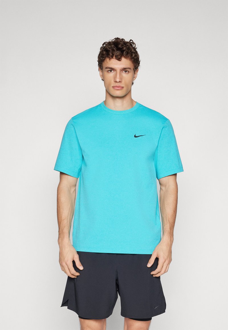 T-shirt de sport turquoise à manches courtes, col ras-du-cou, avec un petit logo Nike noir sur la poitrine. Porté avec un short sombre.