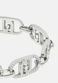 Bracciale in metallo argento con catena interconnessa, uno dei quali è decorato con strass trasparenti, che presenta un design geometrico moderno.