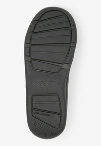 Semelle de chaussure en caoutchouc noir avec une surface texturée, présentant un motif de semelle et une marque claire "NEXT" et "NON MARQUANT".