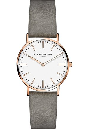 Montre au cadran rond avec un fond blanc, boîtier en or rose et bracelet en cuir gris. Présente des index horaires minimalistes et une couronne unique.