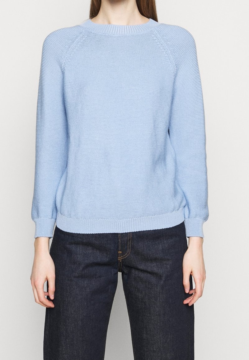 Ljusblått stickat tröja med rund halsringning, raglanärmar och ribbat nederkant och ärmslut. Har en texturerad tyg och en avslappnad passform.