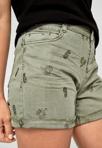Shorts brodés de couleur olive avec un ourlet effiloché, présentant des motifs floraux en fil plus foncé et un design classique à cinq poches.