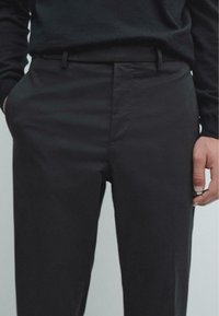 Černé, upravené kalhoty s hladkou texturou. Obsahují boční kapsy a skryté přední zapínání. Slim fit střih zdůrazňuje moderní vzhled.