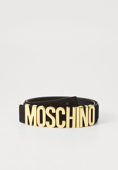Černý semišový pásek s velkou, zlatou sponou ve tvaru loga "MOSCHINO". Pásek má hladkou texturu a nastavitelné patentky.