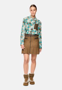 Light blue and white plaid shirt with leopard print accents, paired with a brown pleated skirt featuring a front zipper and pockets. Brown fur-lined boots.