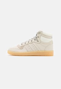 High-top sneakers in light beige leather with gray laces, three side stripes, and a gum rubber sole. Textured accents at the collar.