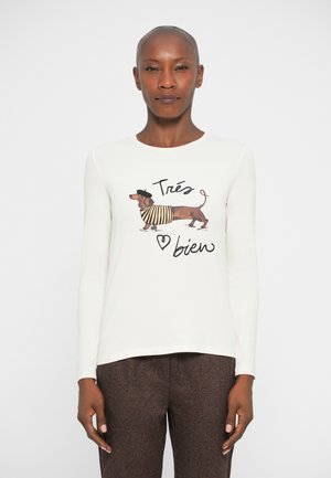 Hvit langermet skjorte med et grafisk motiv av en dachshund i stripete skjorte og beret, med teksten "Très bien" under designet.