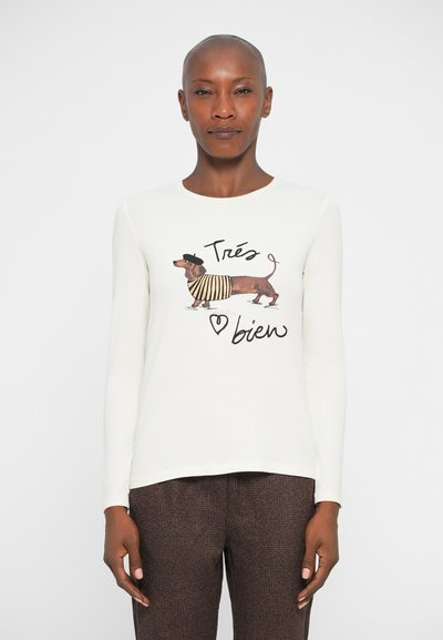 Camicia bianca a maniche lunghe con una grafica di un dachshund in una maglietta a righe e un berretto, con la scritta "Très bien" sotto il design.