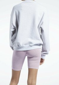 Grå oversize sweatshirt med ribbade ärmar som matchas med ljusrosa tajta shorts, som visar en mjuk, slät textur.