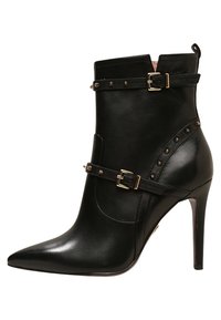 Bottines en cuir noir avec un bout pointu, des boucles dorées et des accents cloutés. Elles présentent un talon haut et une texture lisse.