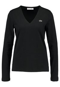 Černé tričko s dlouhým rukávem ve tvaru V vyrobené z bavlny, s malým bílým logem Lacoste na levé části hrudi. Hladký povrch, přiléhavý střih.