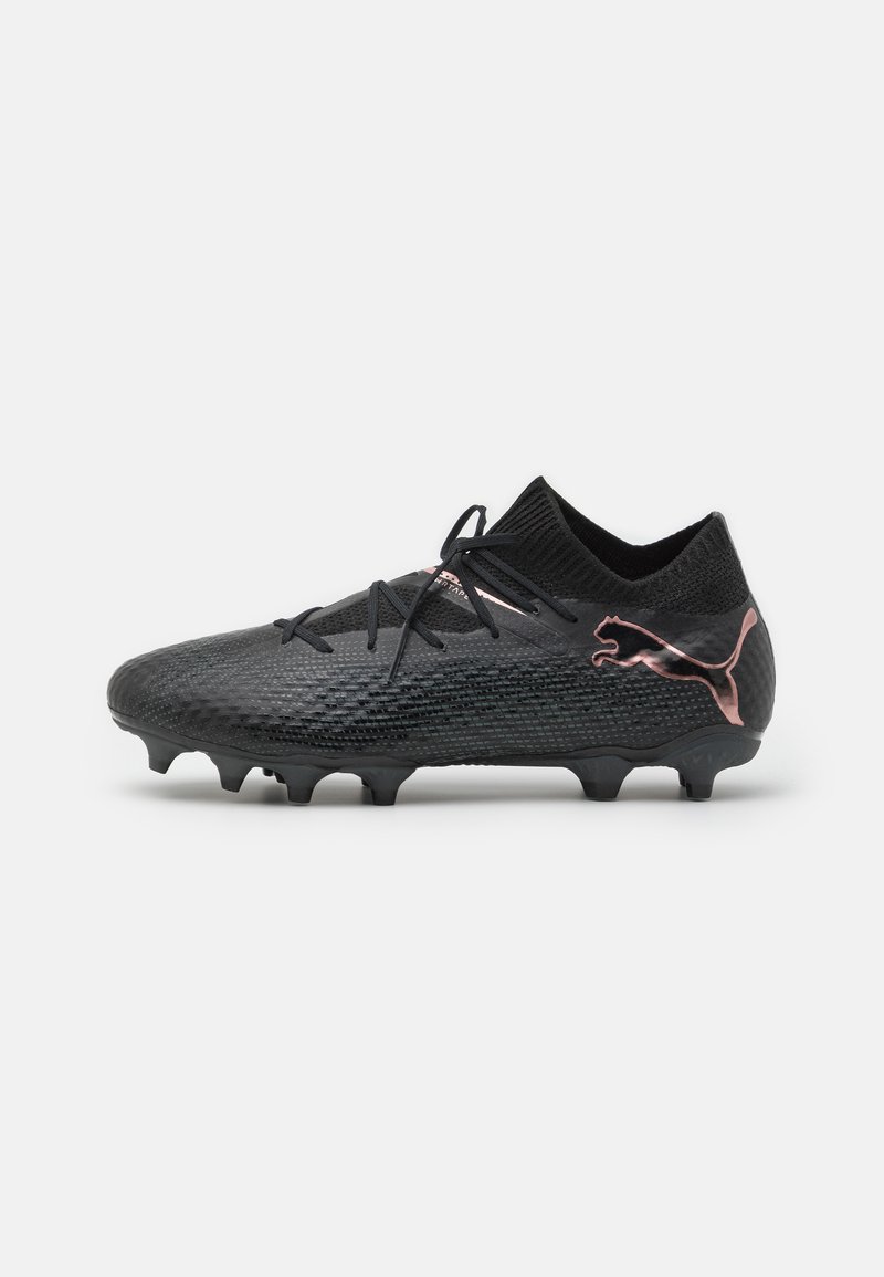 Scarpe da calcio atletiche nere con parte superiore texturizzata, chiusura con lacci e logo con accento rosa. Presenta un design a basso profilo e tacchetti sagomati.