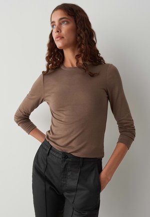 Bruin lang袖 shirt van een zachte stof, fitted vorm, gecombineerd met hoge zwarte broek met knoopsluiting en zijzakken.