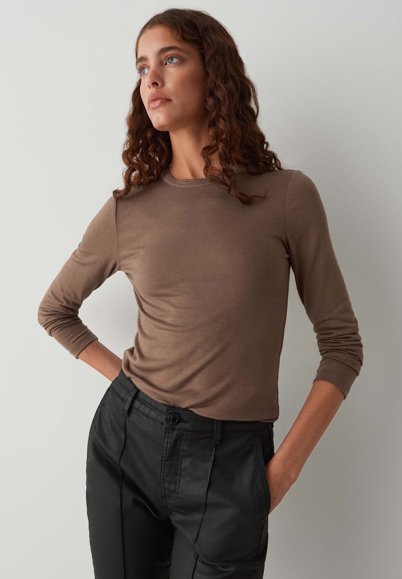 Bruin lang袖 shirt van een zachte stof, fitted vorm, gecombineerd met hoge zwarte broek met knoopsluiting en zijzakken.