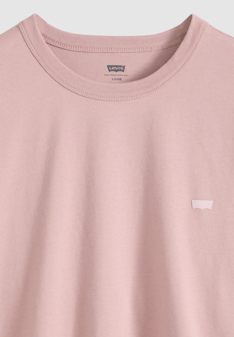 T-shirt Levi's à col rond ample de couleur rose clair avec un petit patch logo sur la poitrine gauche et un col cousu.