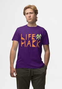 Fialové bavlněné tričko s nápisem "LIFE HACK" v oranžové barvě a grafikou zeleného palmového listu. Krátké rukávy a standardní střih.