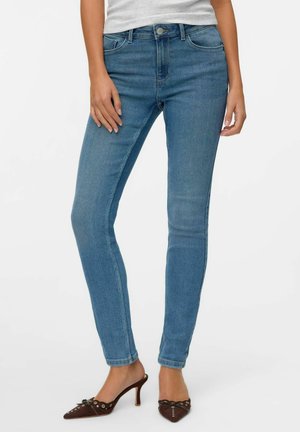 Hellblaue, enge Jeans aus Denim mit einem klassischen Fünf-Taschen-Design und einem hochgeschnittenen Bund. Kombiniert mit braunen, spitzen High Heels.
