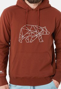 Felpa marrone in cotone, con un design geometrico di un orso bianco sulla parte anteriore, tasca a kangaroo e cordini sul cappuccio.