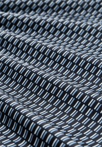 Textil mit einem dunkelblauen Hintergrund und einem geometrischen Muster aus wechselnden hellblauen und weißen rechteckigen Formen. Glatte Textur.