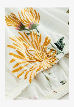 Floral fabric featuring yellow and pink designs on a white background. Elasticated hem with visible stitching detail. Soft texture.