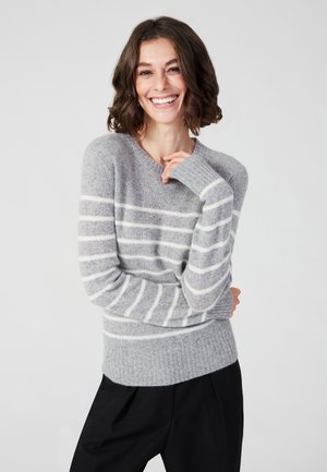 Maglione grigio a righe realizzato in materiale morbido, con strisce orizzontali bianche, scollo a V e polsini a costine, abbinato a pantaloni neri.