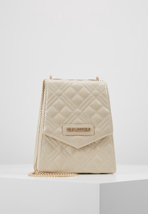 Kremowa pikowana skórzana torebka na ramię z złotym łańcuszkiem i złotą tabliczką z napisem „LOVE MOSCHINO” na przedniej klapie.