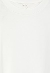White cotton T-shirt with a round neckline and short sleeves, featuring a smooth texture and minimalistic design. Tags visible near the collar.