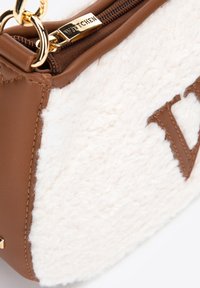 Hnědá kožená taška na rameno s krémovým beránkem, která má zlatý zip s brandingem "WITTCHEN" a výrazným detailem loga.