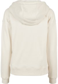 Sweat à capuche couleur crème avec manches longues, poignets et ourlet côtelés, vu de dos montrant une capuche avec des coutures visibles.