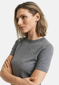Maglione grigio a maniche corte con scollatura tonda, dal tessuto liscio e dal design attillato. Collo a costine e tessuto morbido, stile casual e versatile.