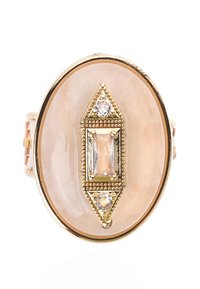 Oval-shaped ring featuring a smooth, pale stone center, framed by intricate gold accents and three small, clear gemstones.